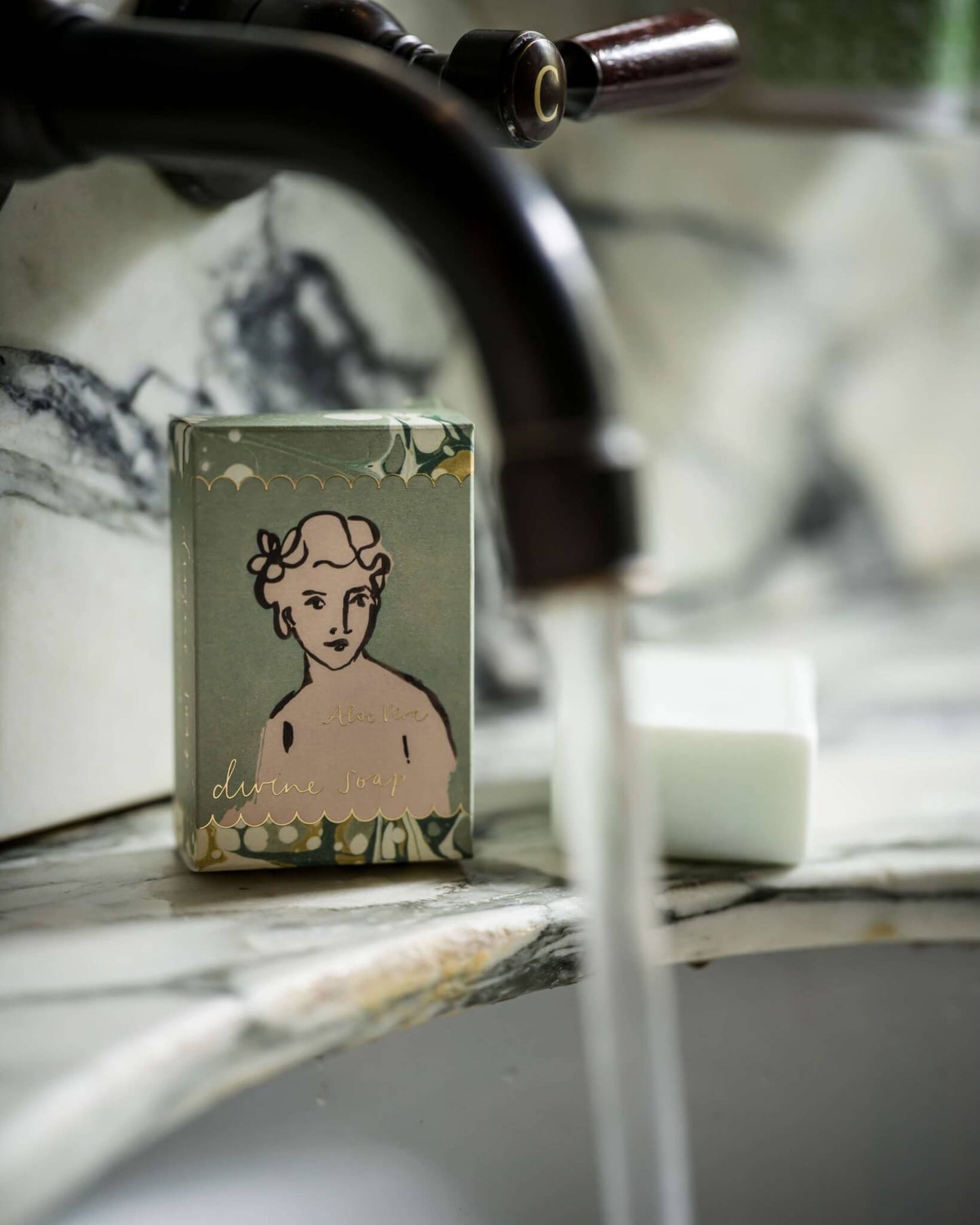 A box of soap with a printed design of a woman's face on a marble bathroom surface.