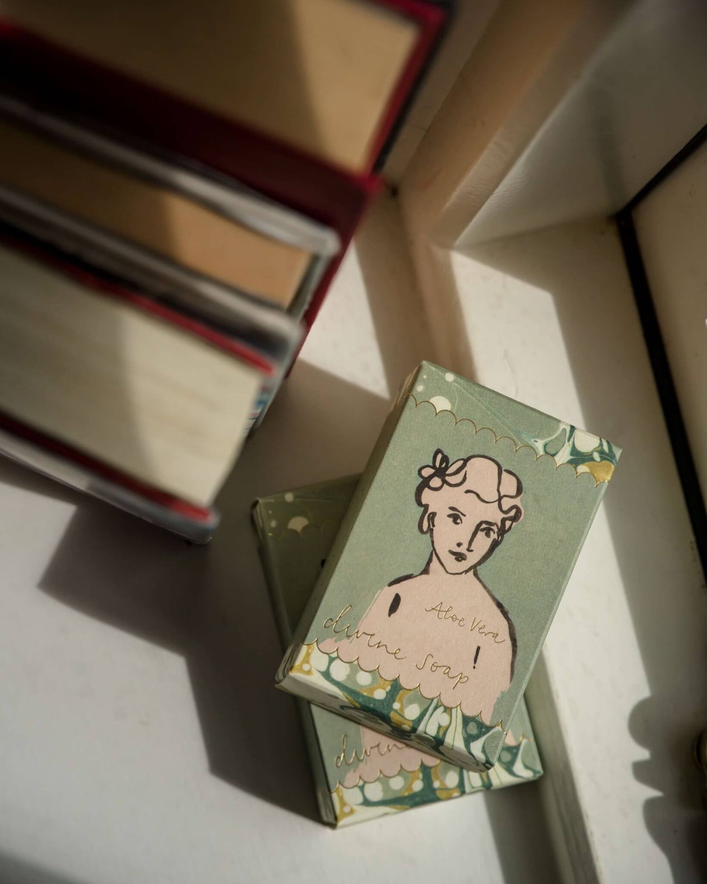 Two soap boxes with vintage-style illustrations on a window sill.