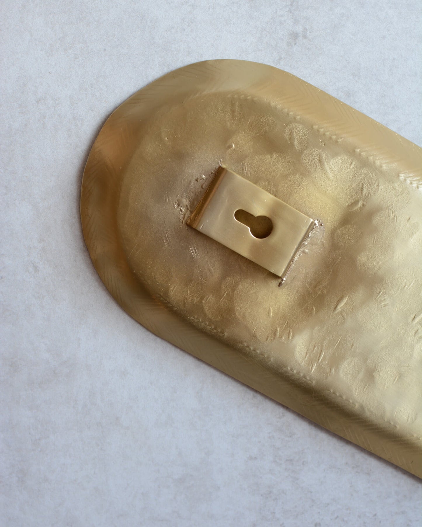 Reverse of a brass candle wall sconce, showing picture hook on the back for hanging.