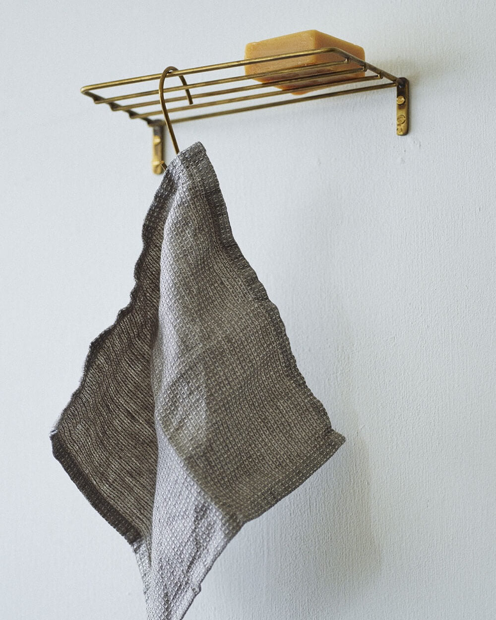 A solid brass wire wall shelf for bathroom or kitchen storage.
