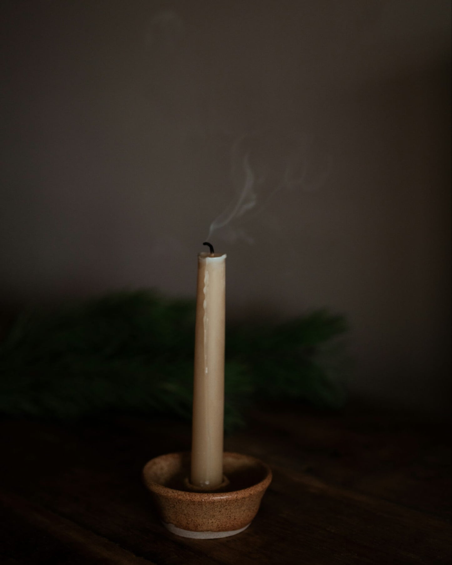 A beeswax candle, in a ceramic candle holder.