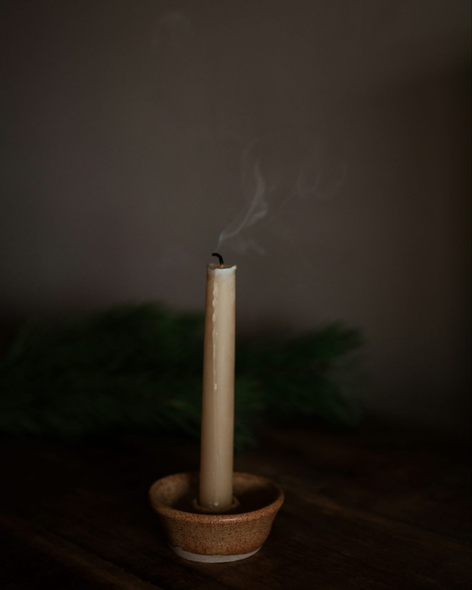 A beeswax candle, in a ceramic candle holder.