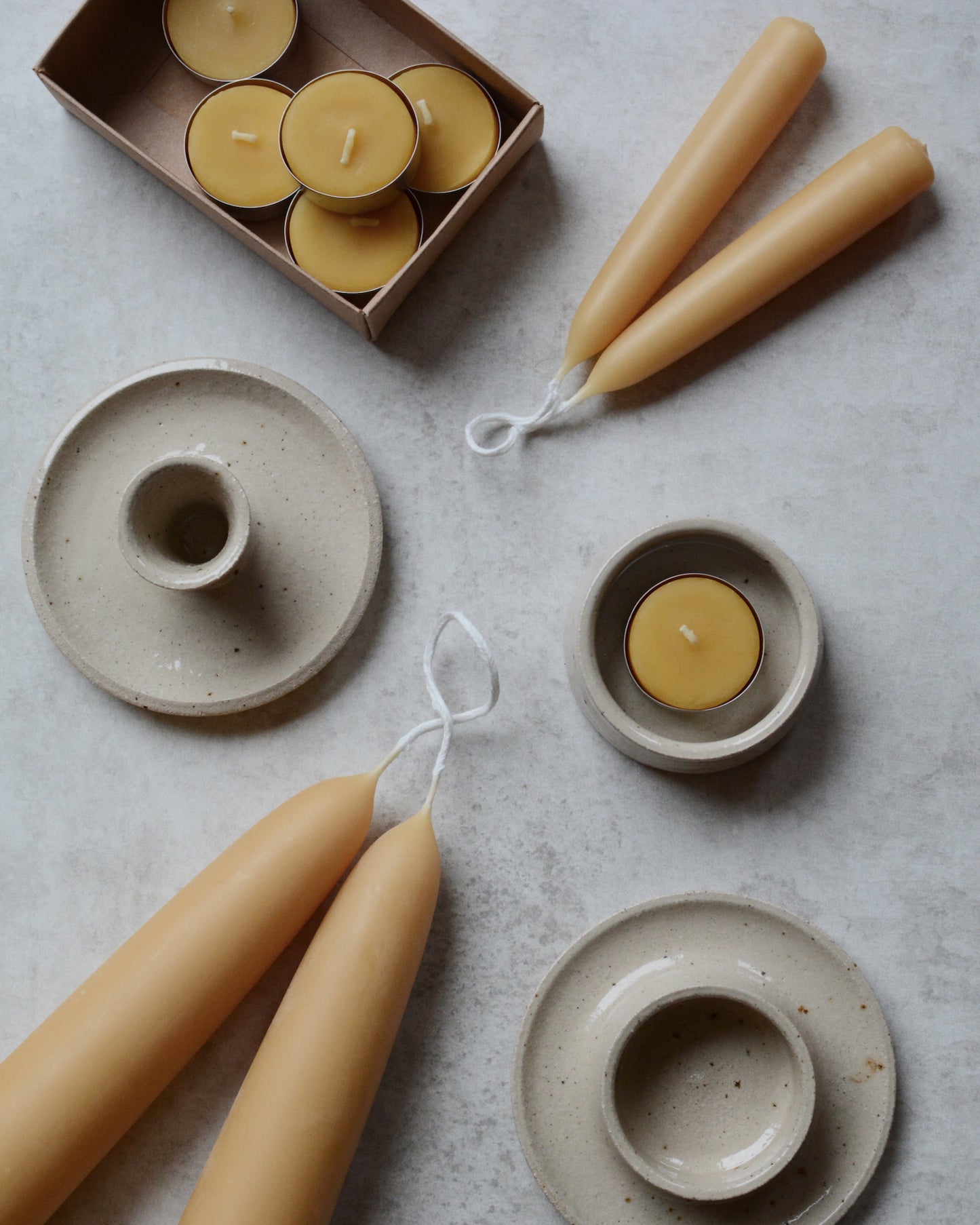 A collection of beeswax candles and ceramic candle holders.