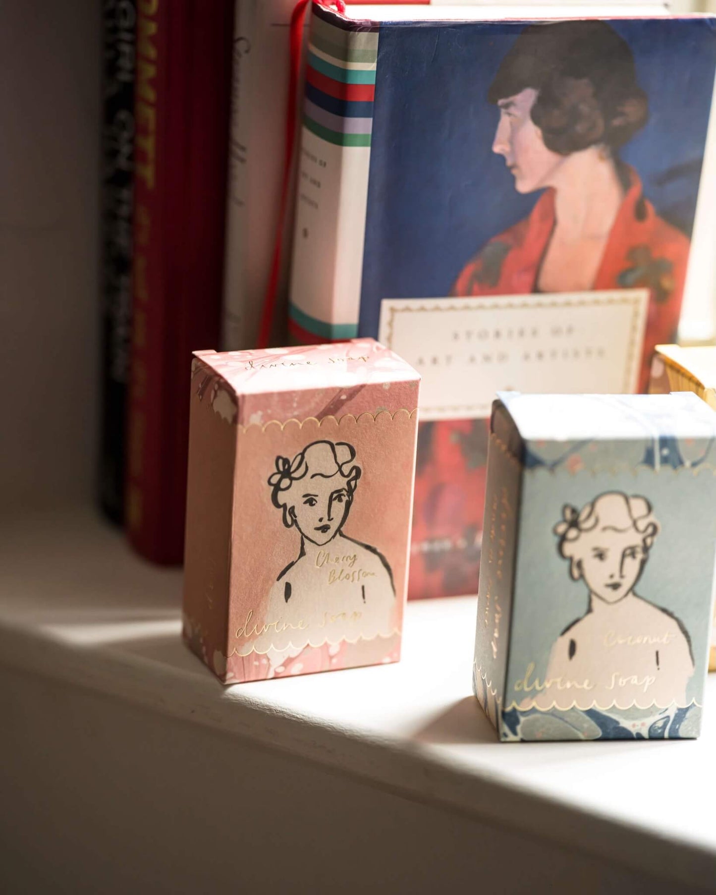 Two decorative soap boxes with vintage-style illustrations on a shelf.
