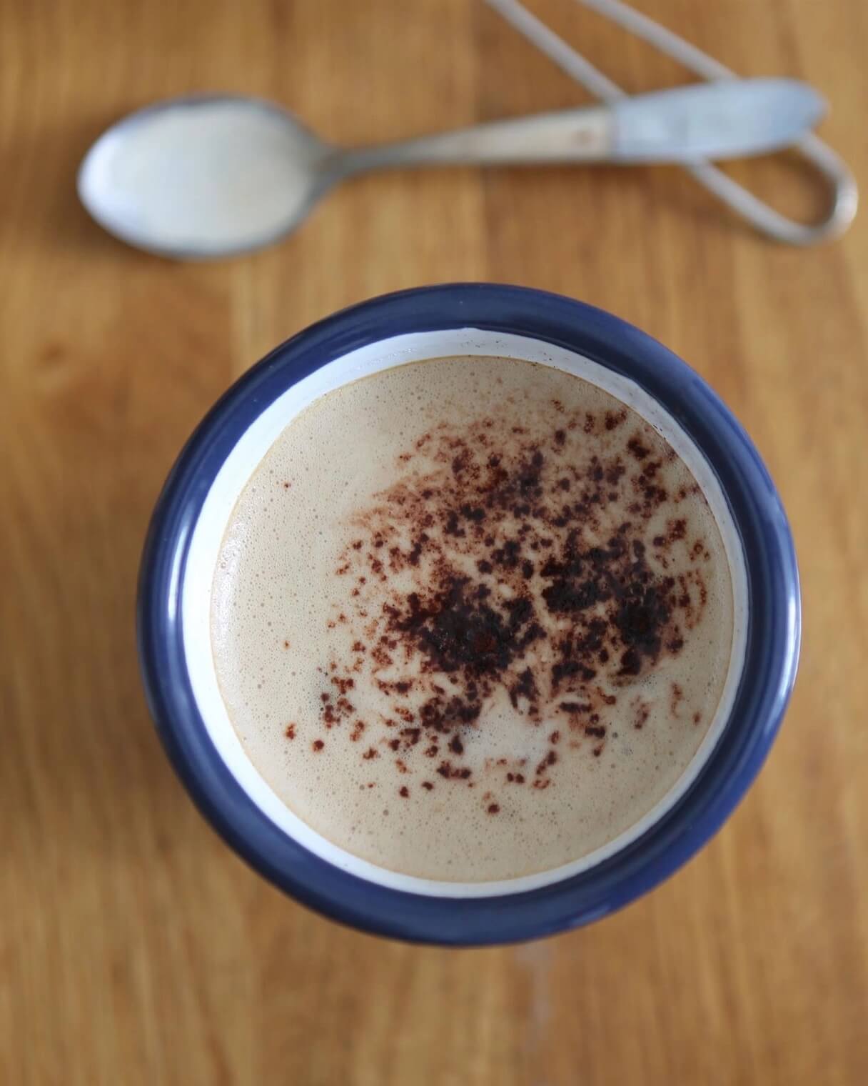 A classic white enamel tumbler with navy rim, shown with hot chocolate inside.