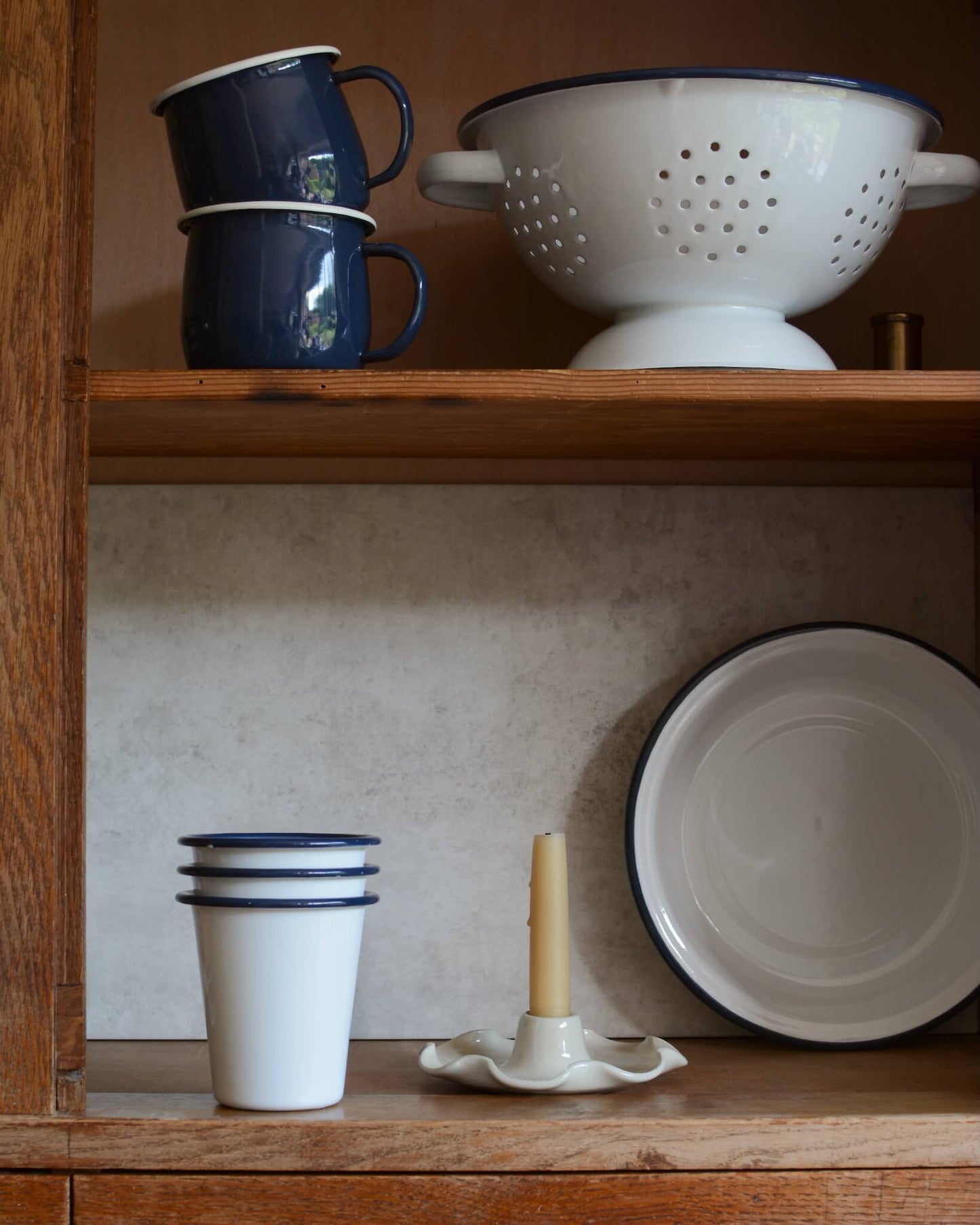 A collection of classic white and blue enamel kitchenware pieces, including mugs, dishes and colander.