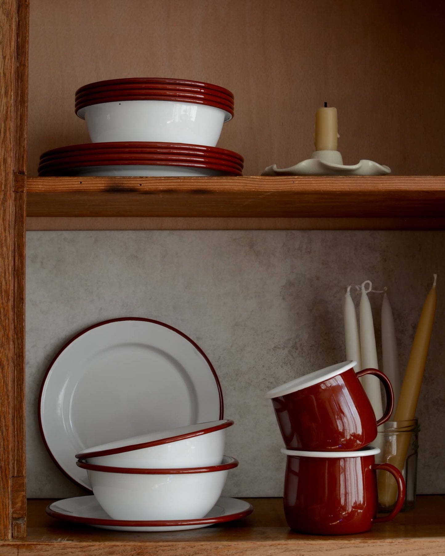 A collection of white and burgundy red enamel bowls, plates and cups.