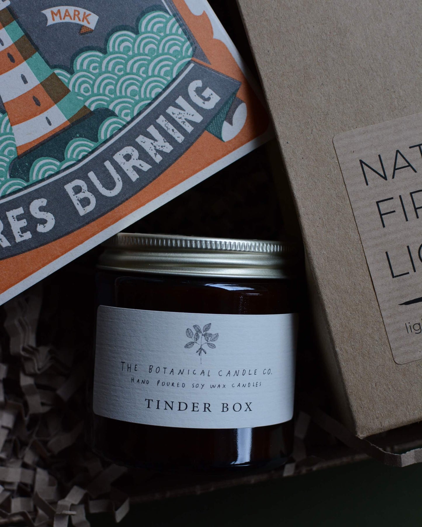 Gift box, containing an amber jar candle, box of matches with a lighthouse design and a pack of natural firelighters.