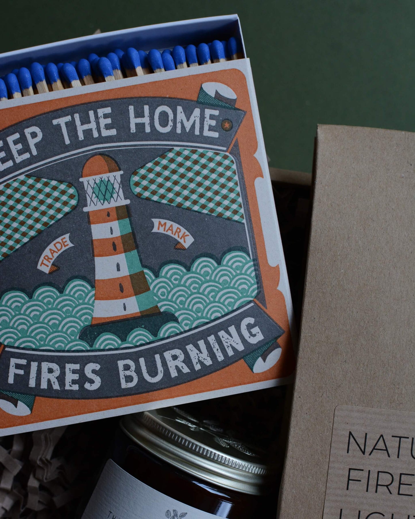 Gift box, containing an amber jar candle, box of matches with a lighthouse design and a pack of natural firelighters.