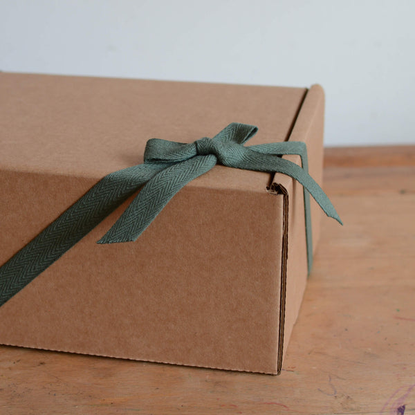 A kraft gift box with green ribbon, tied in a bow.