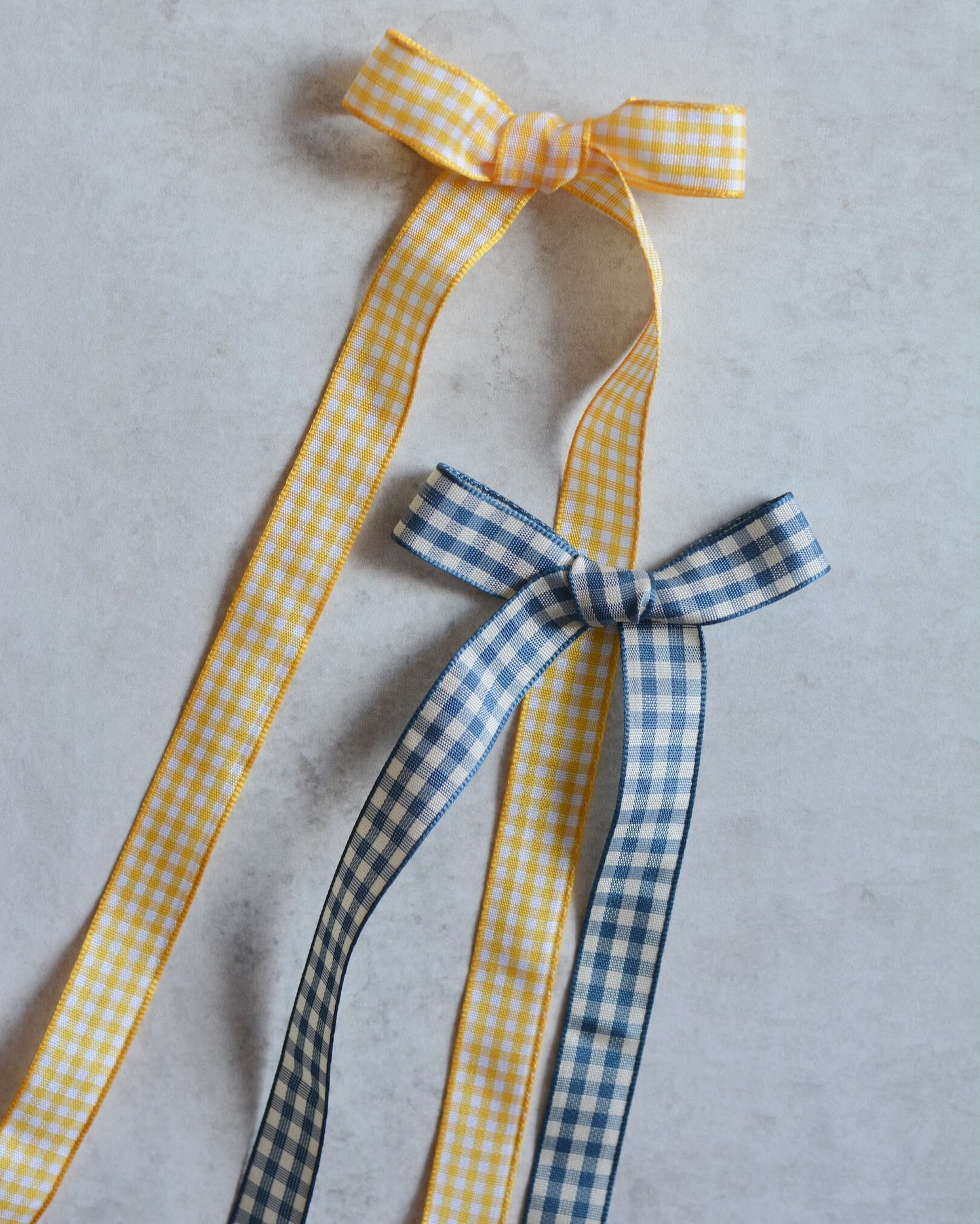 A yellow and white gingham bow and a blue and white gingham bow.