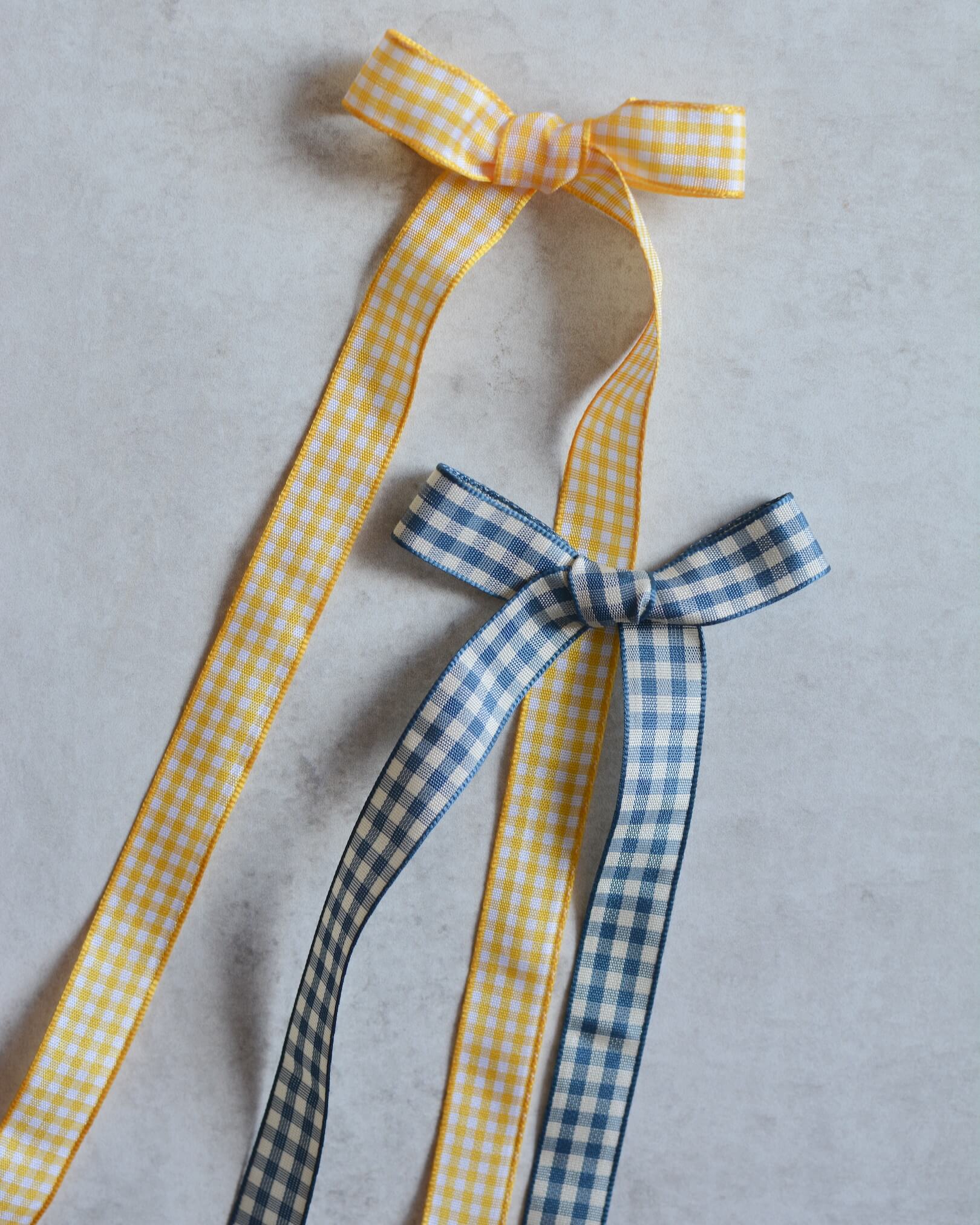 A yellow and white gingham bow and a blue and white gingham bow.