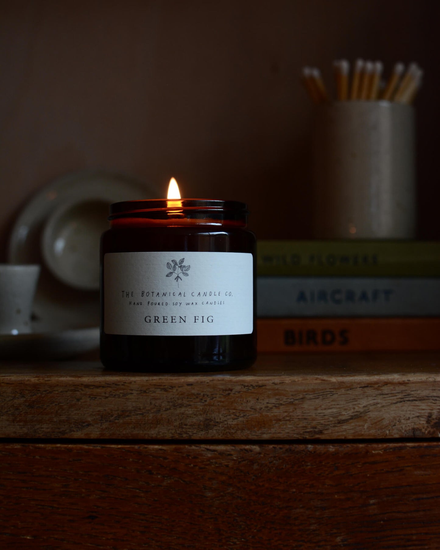 A lit green fig scented soy candle by The Botanical Candle Co.