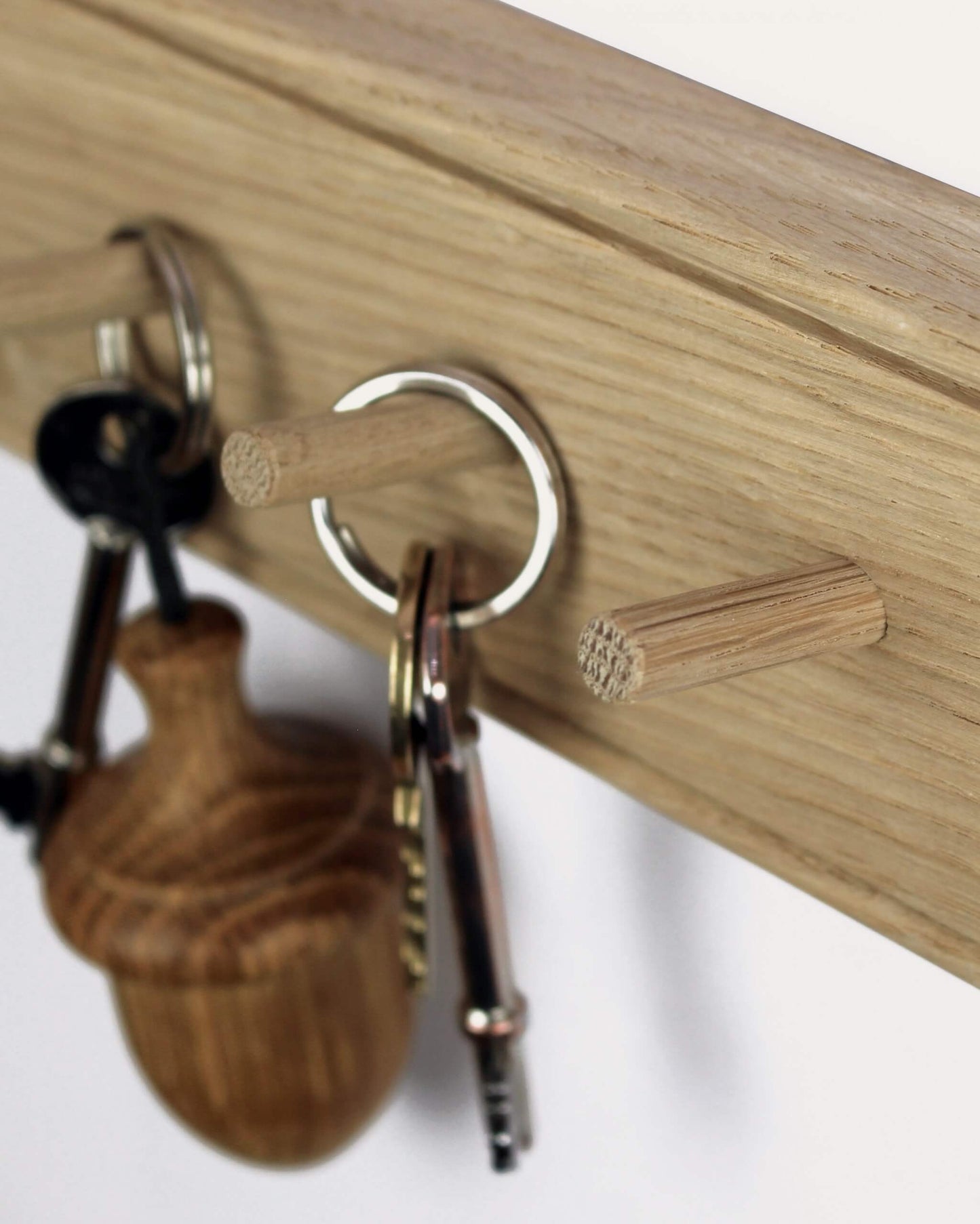 An oak key rack with 5 hooks by Creamore Mill, shown with keys
