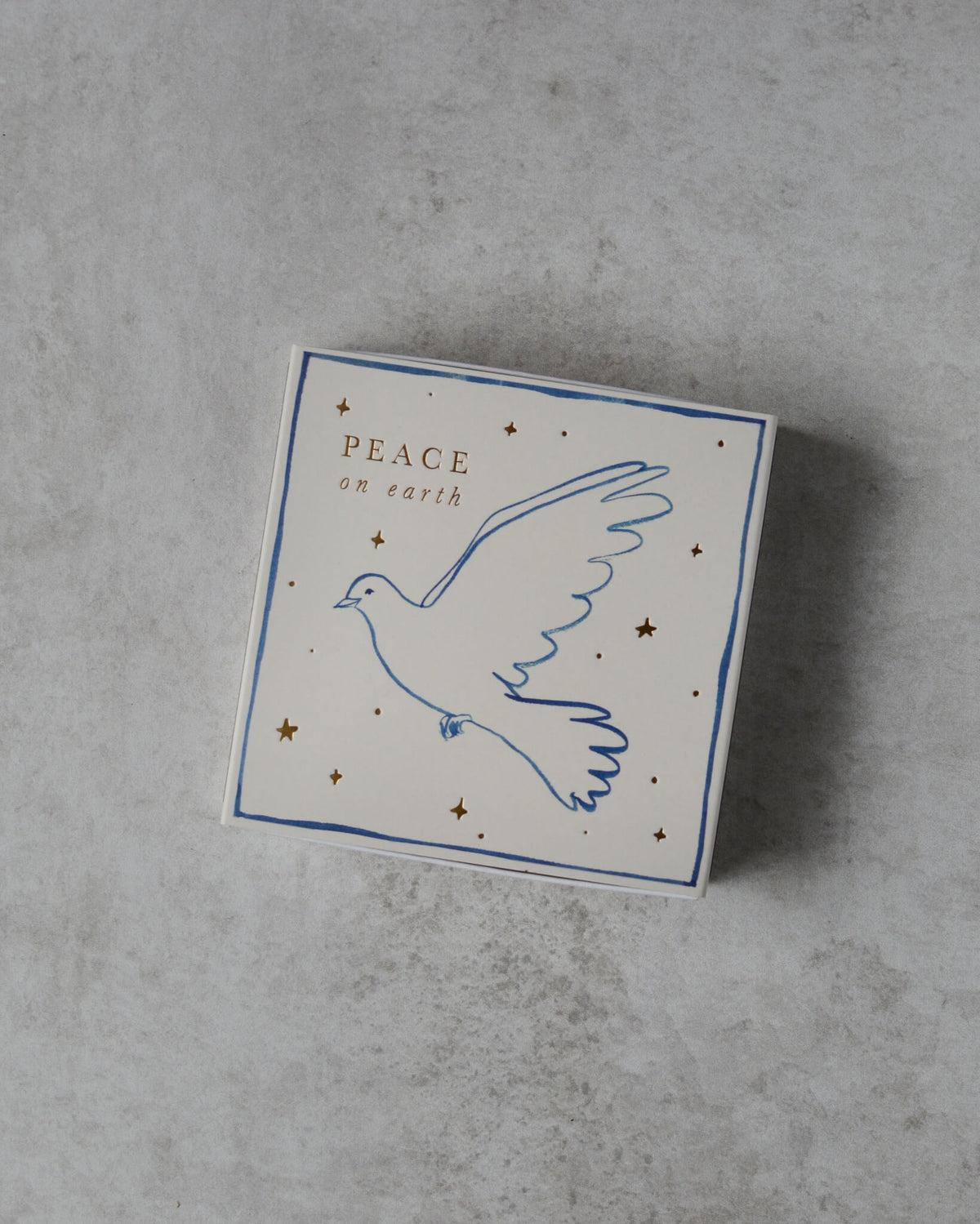 A white matchbox, with a dove illustration and 'peace on earth' lettering.