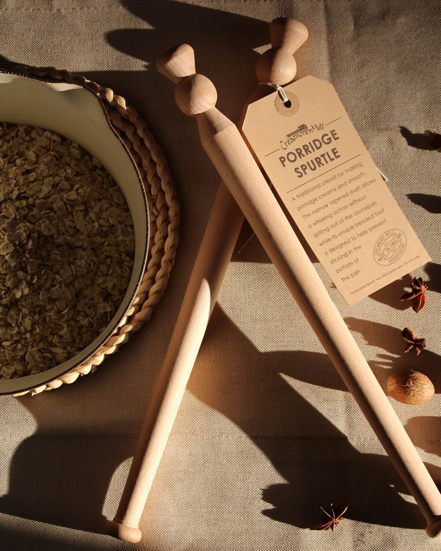 Wooden porridge spurtle next to porridge oats.