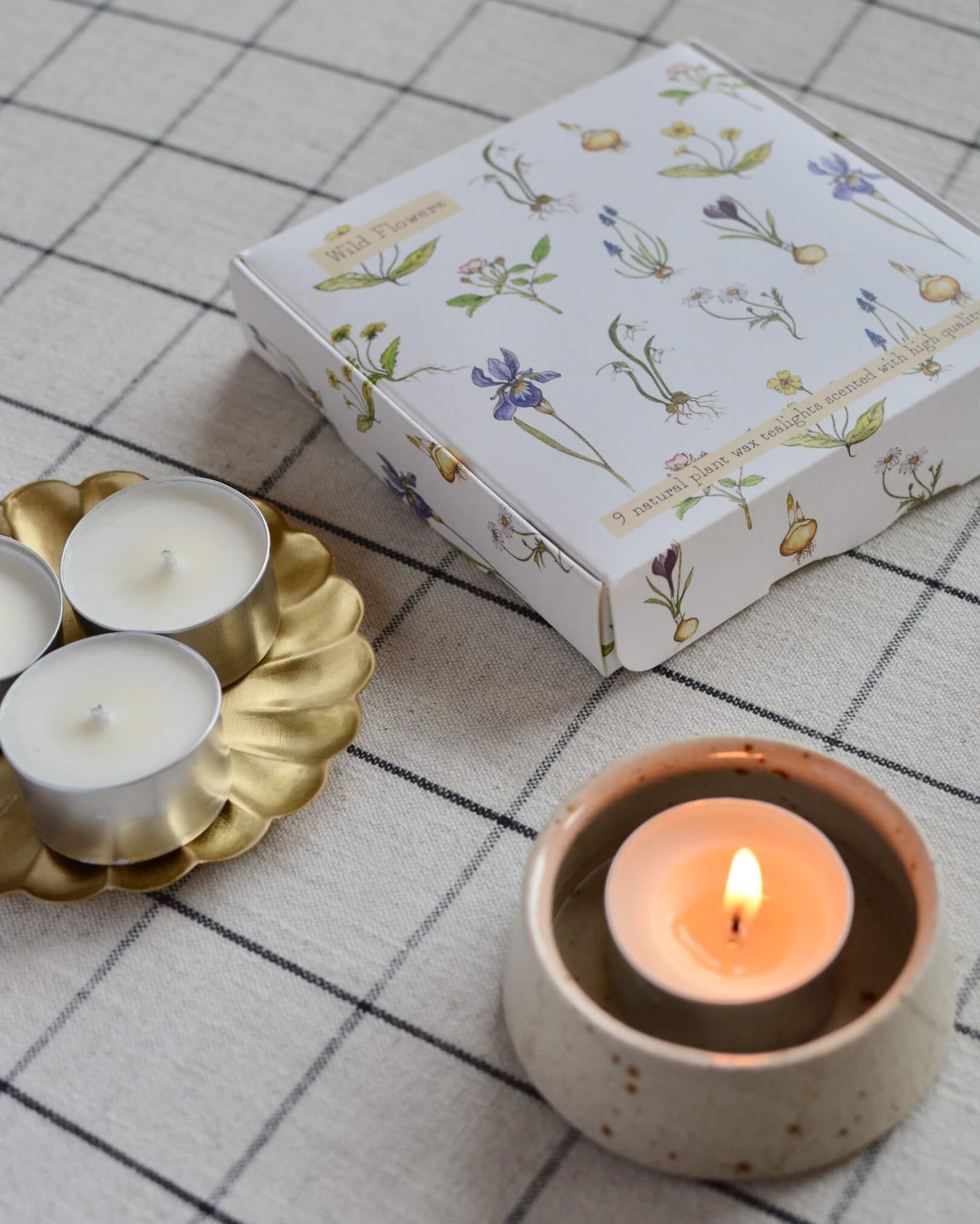 A lit scented tealight, inside of a ceramic tealight holder.