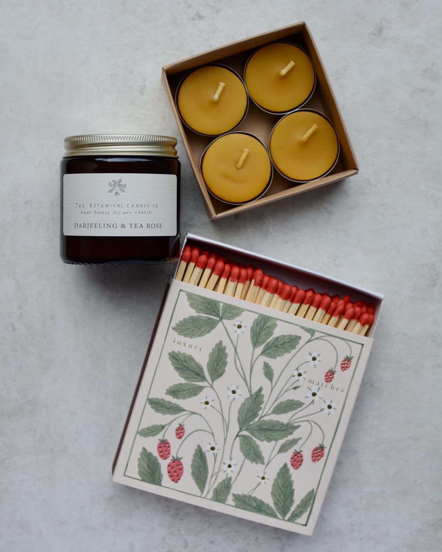 A candle gift box containing a scented rose candles, 4 beeswax tea lights and a box of strawberry-design matches.