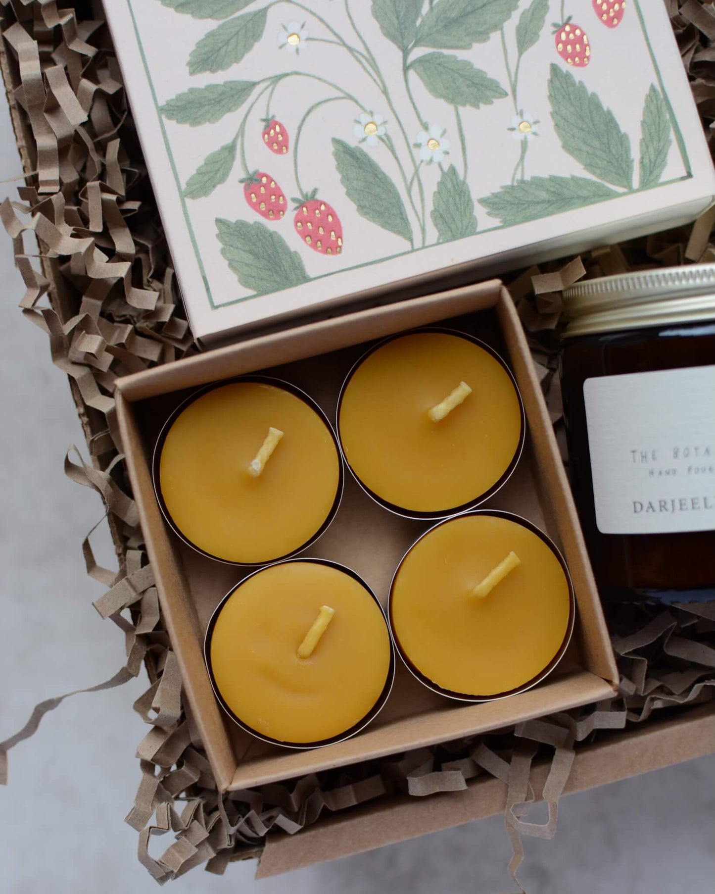 A candle gift box containing a scented rose candles, 4 beeswax tea lights and a box of strawberry-design matches.