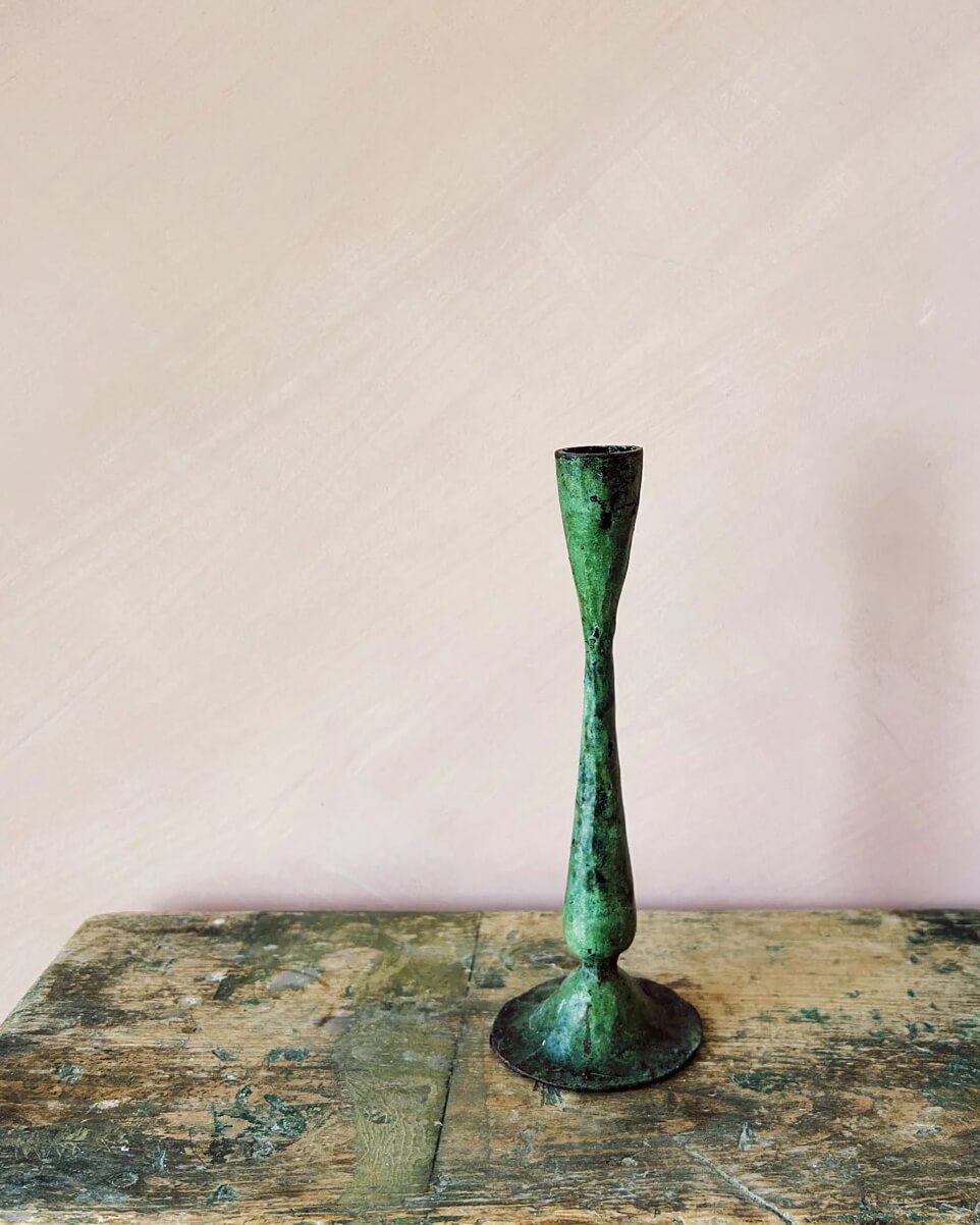 A tall green verdigris candle holder, for taper candles.