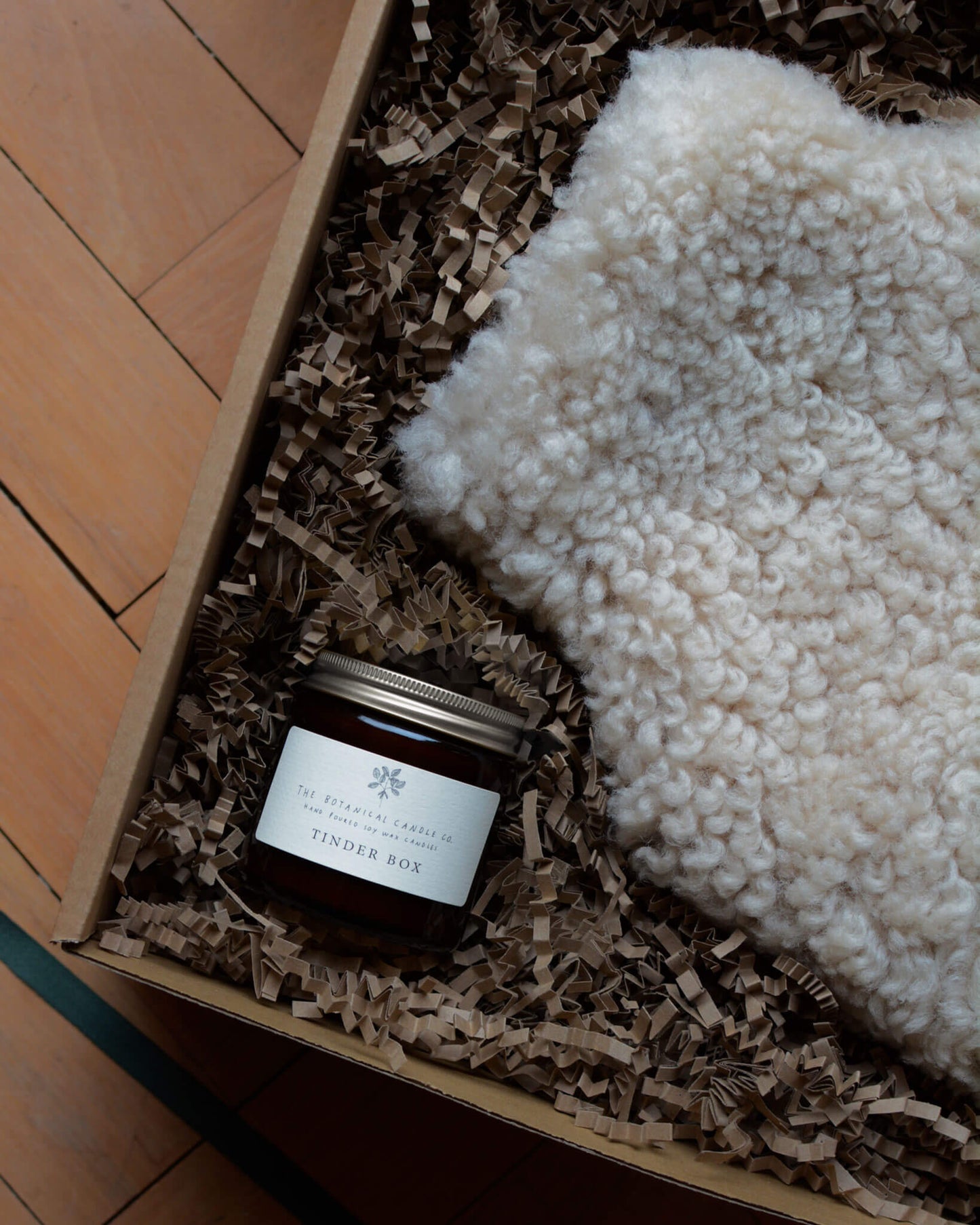 Tinder Box scented candle by The Botanical Candle Co. next to a sheepskin hot water bottle.
