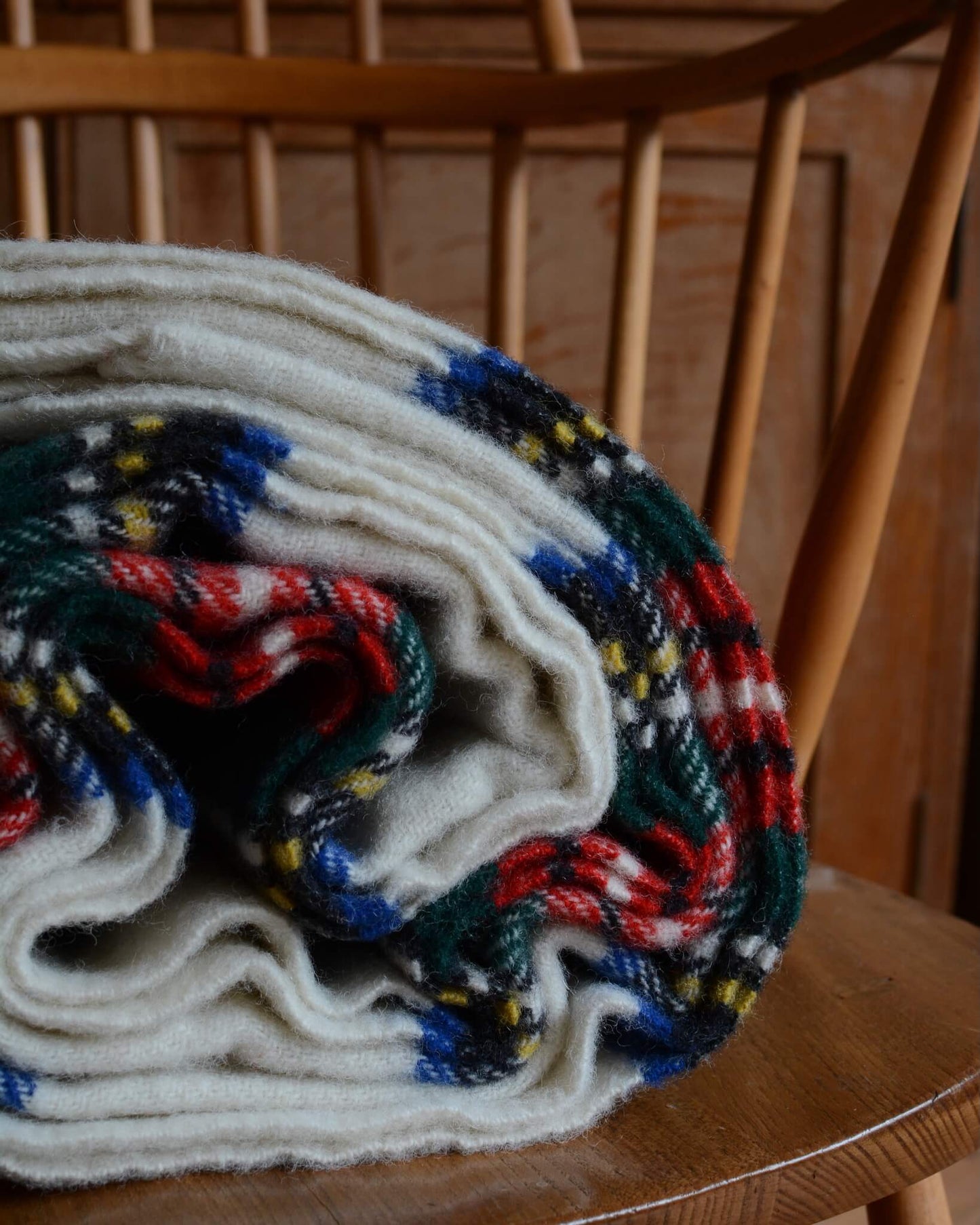 Close up of a rolled-up plaid wool blanket with colourful pattern.