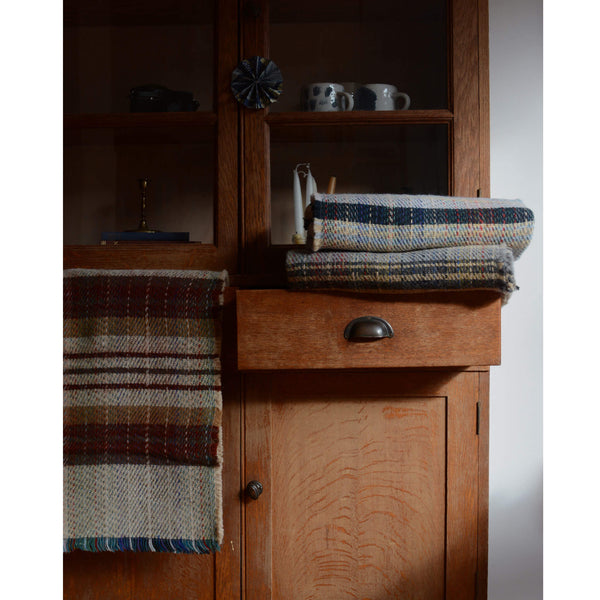 Recycled wool Tweedmill blankets shown in front of a vintage wooden cabinet.