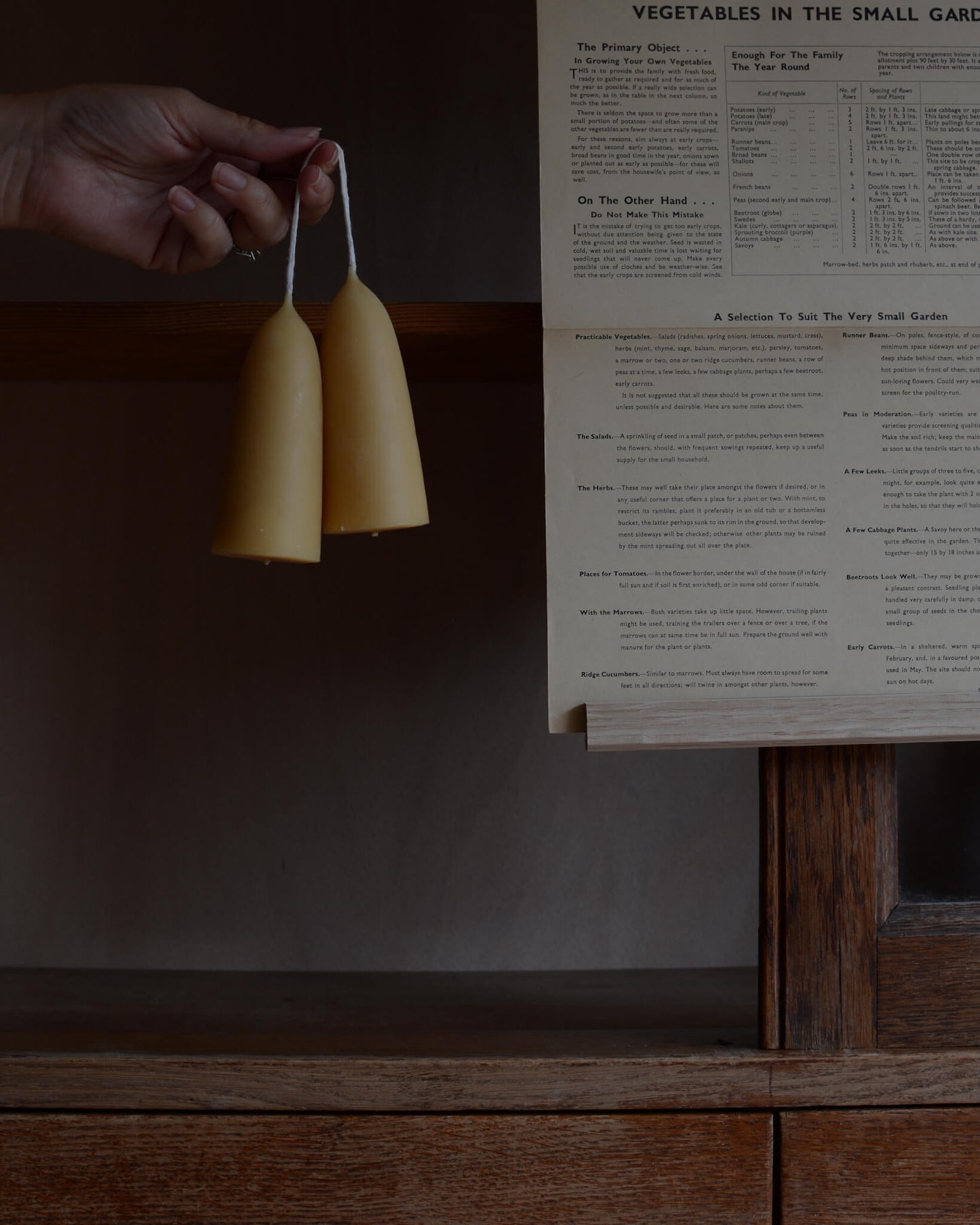 A pair of beeswax candles, shown held in a hand for scale.