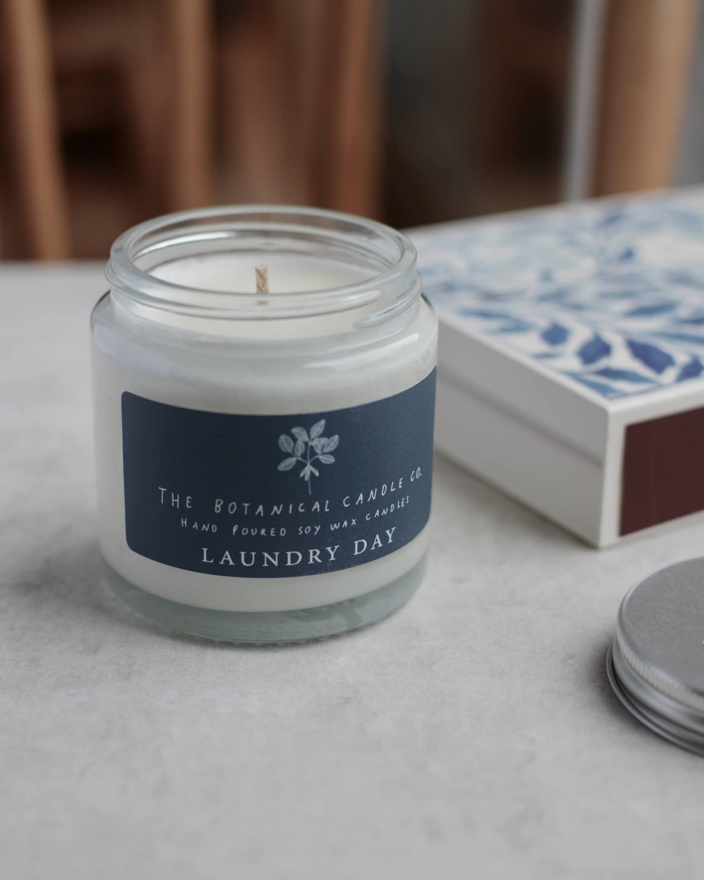 A scented soy candle in a glass jar with a blue label, which reads Laundry Day.