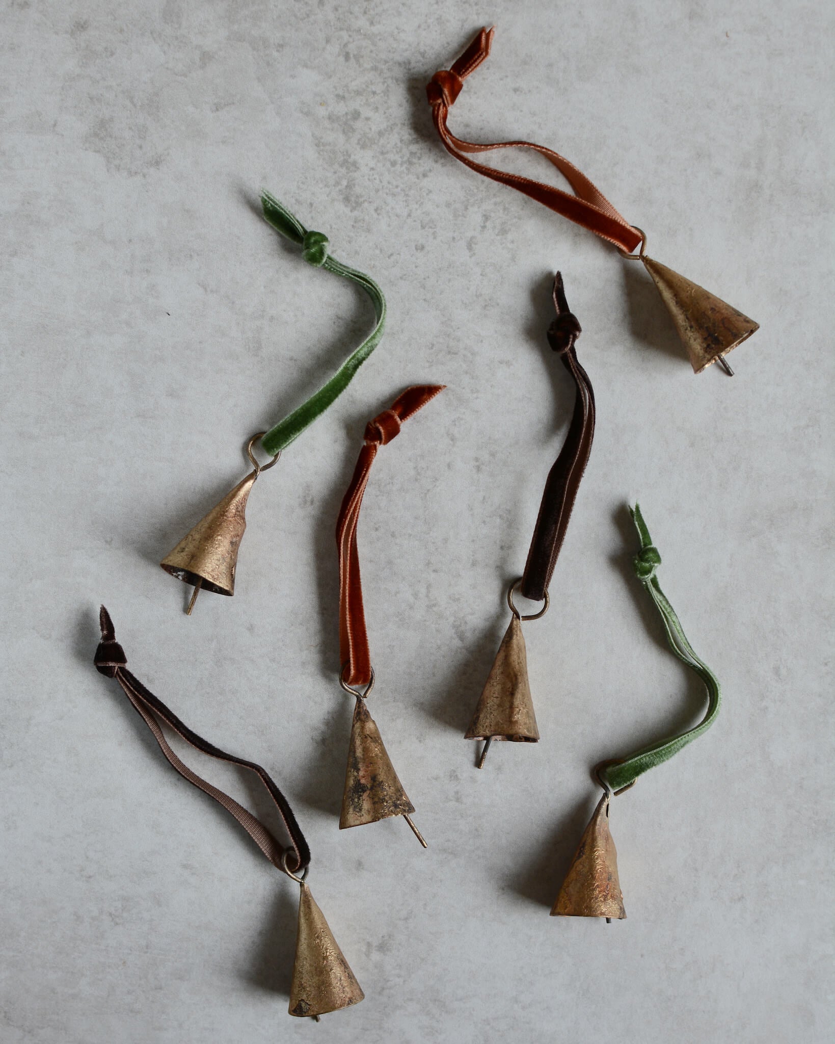 Brass bell Christmas ornaments, strung with velvet ribbon in rich tones.