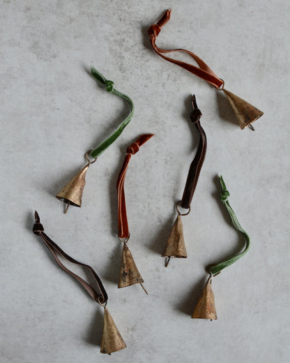 Brass bell Christmas ornaments, strung with velvet ribbon in rich tones.
