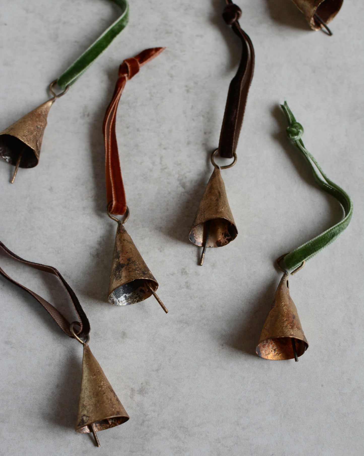 Brass bell Christmas ornaments, strung with velvet ribbon in rich tones.
