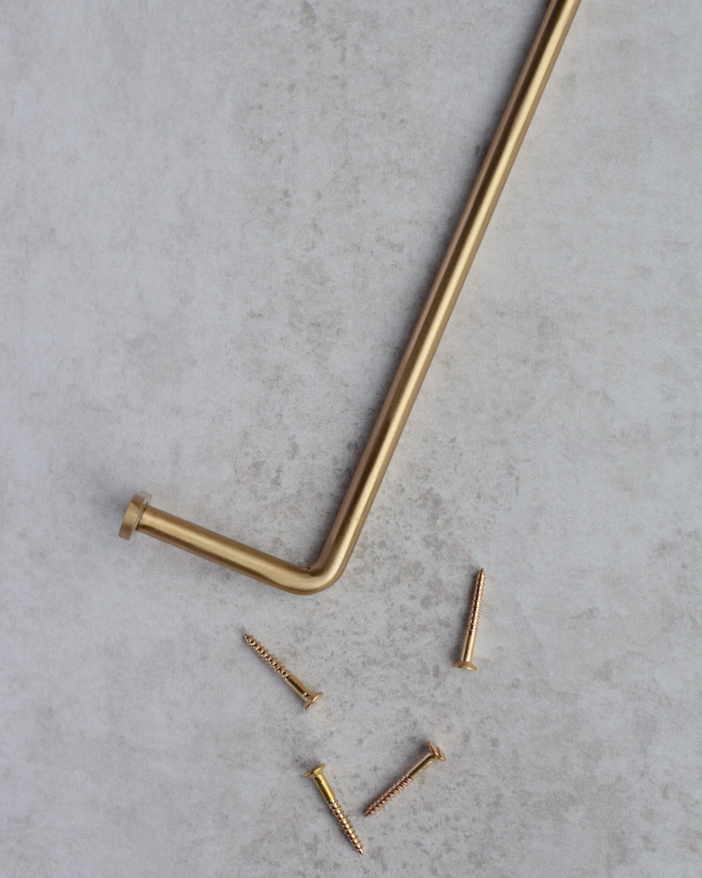 A solid brass wall-mounted hanging rail and screws.