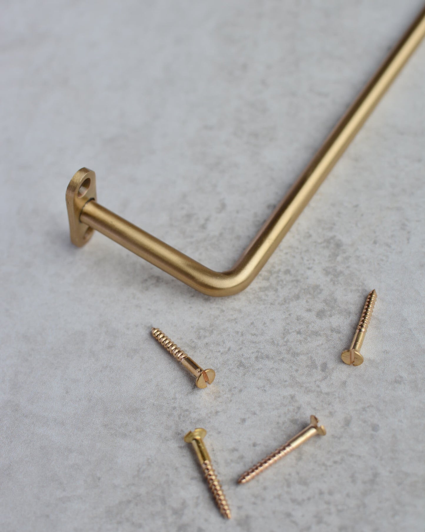 A solid brass wall-mounted hanging rail and screws.