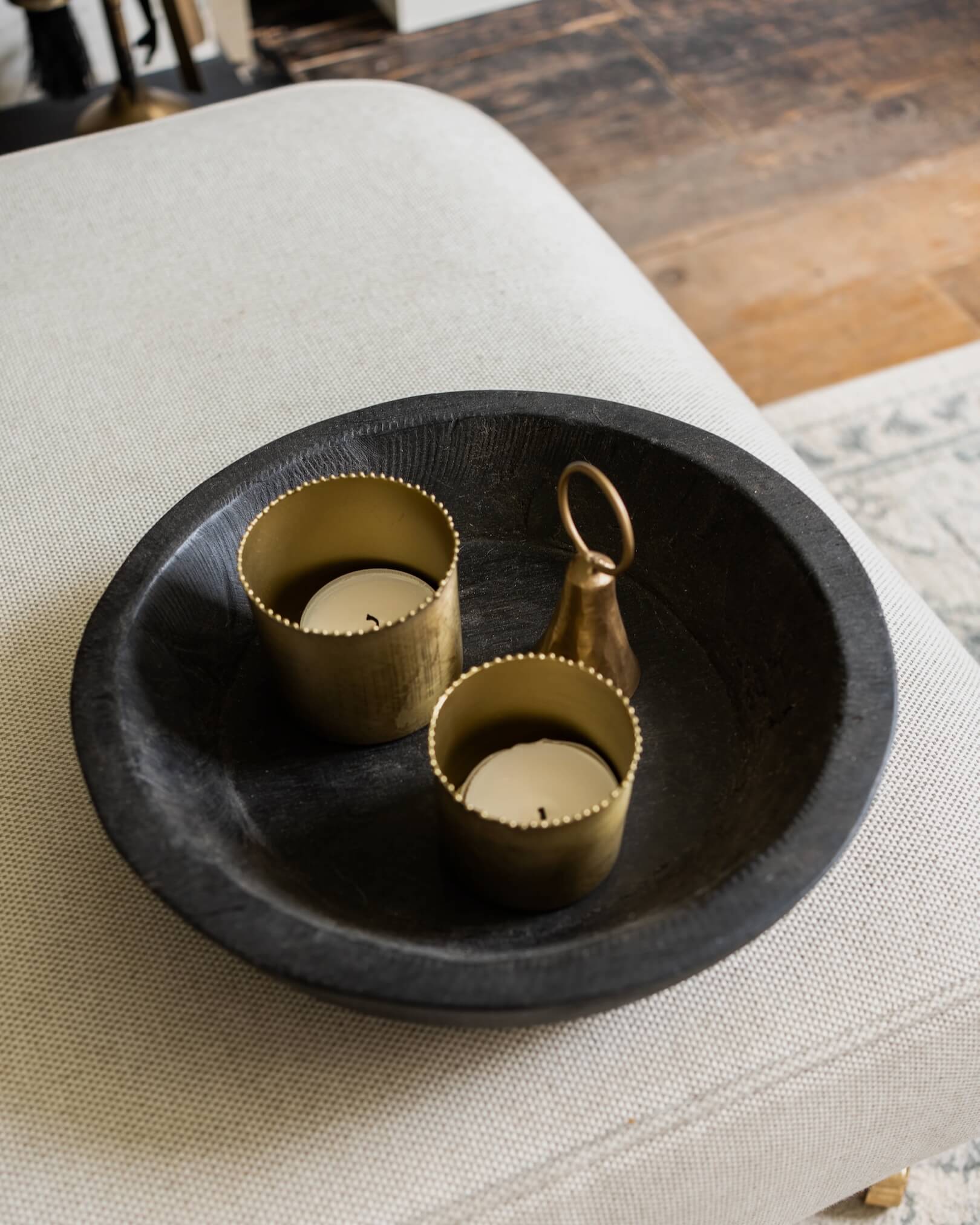 A set of 2 solid brass tea light holders, with beaded detailing around the rim. Shown in a wooden bowl.