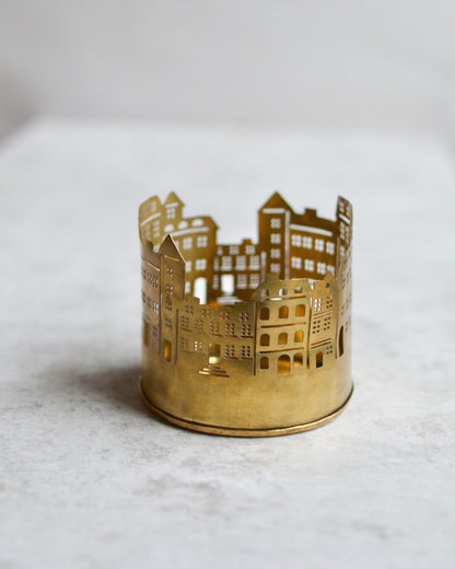 Brass tealight candle holder shaped like a cityscape on a white background.