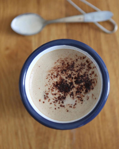A classic white enamel tumbler with navy rim, shown with hot chocolate inside.
