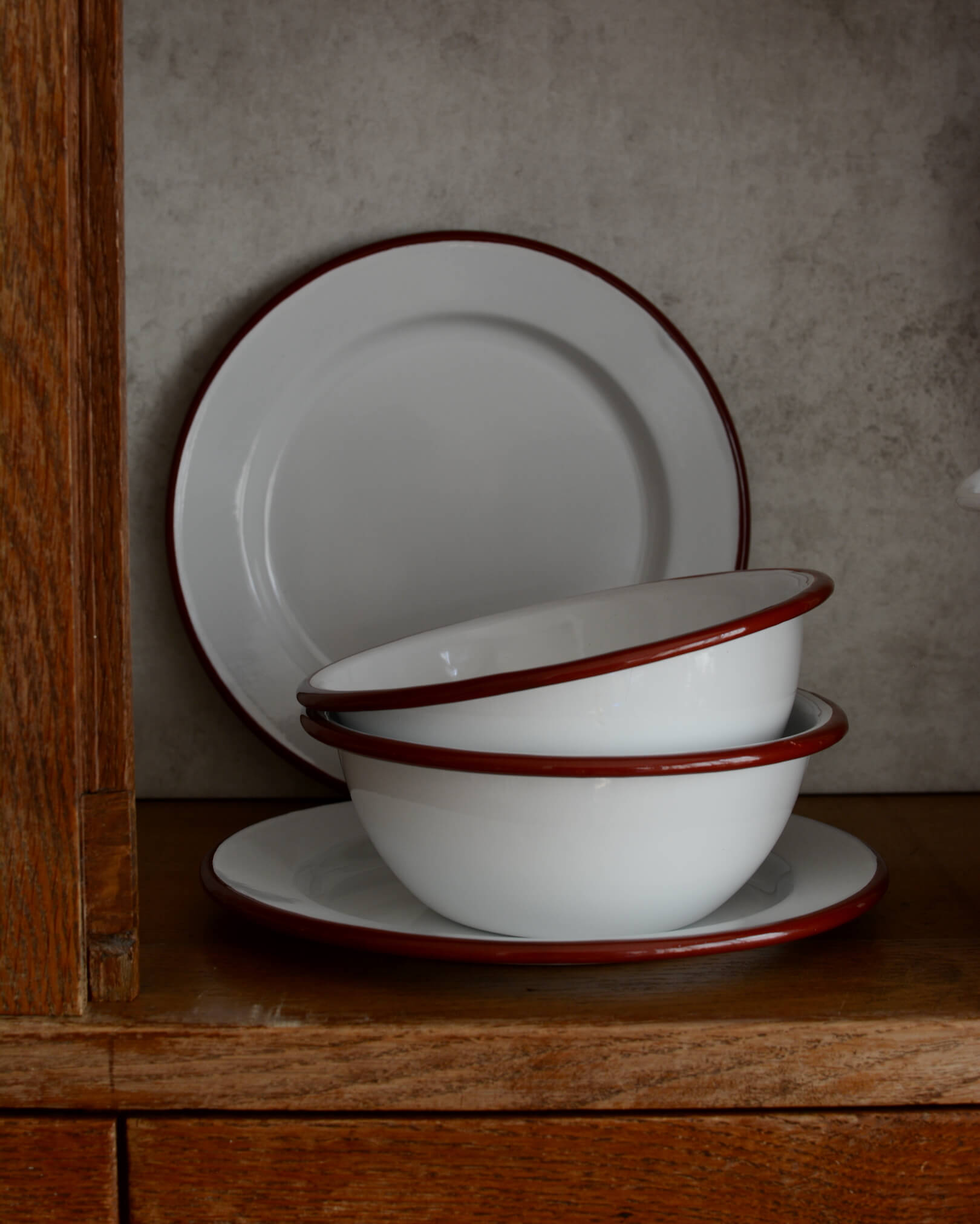 A set of white and burgundy red enamel bowls and plates.