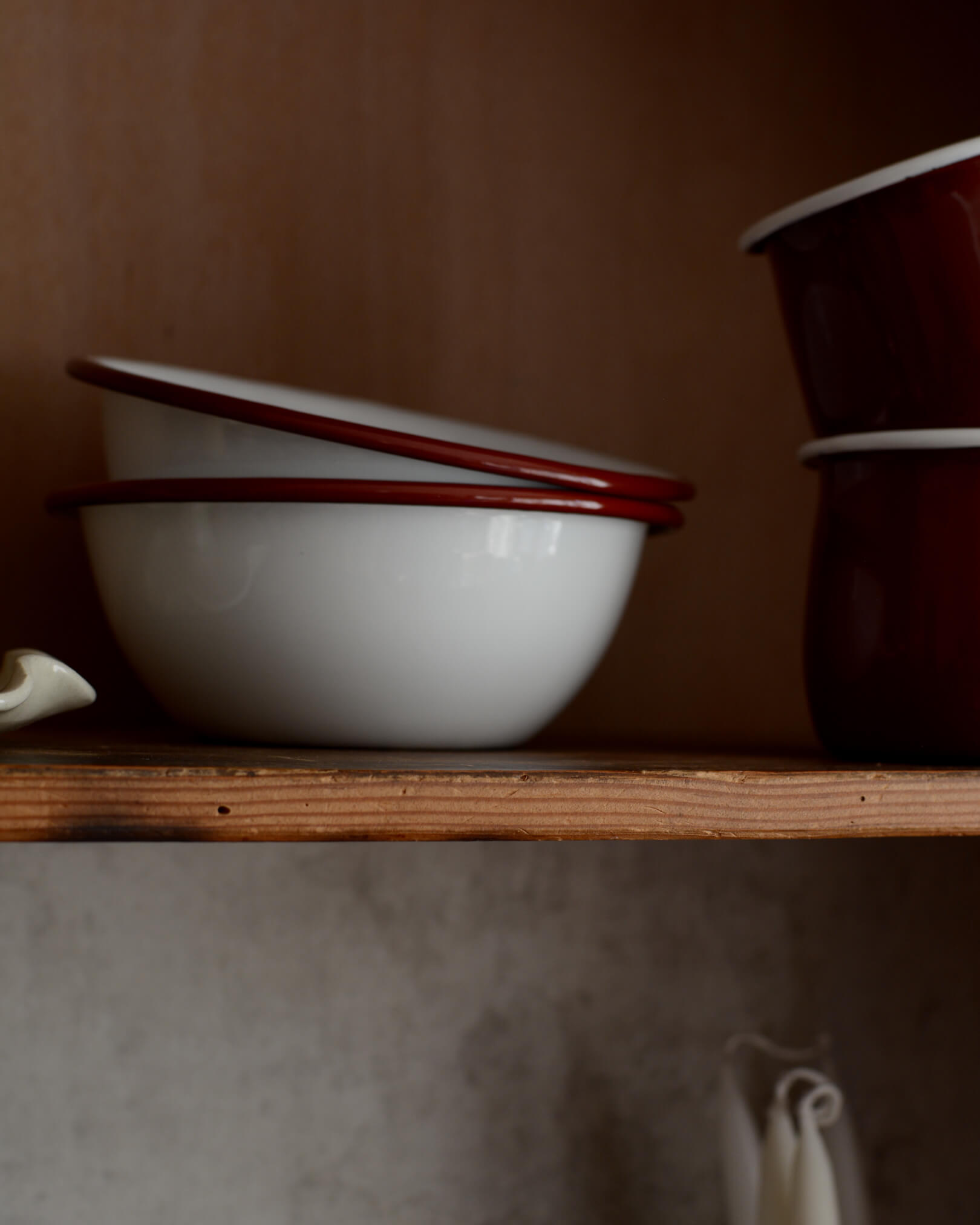 A pair of white and burgundy red enamel bowls.