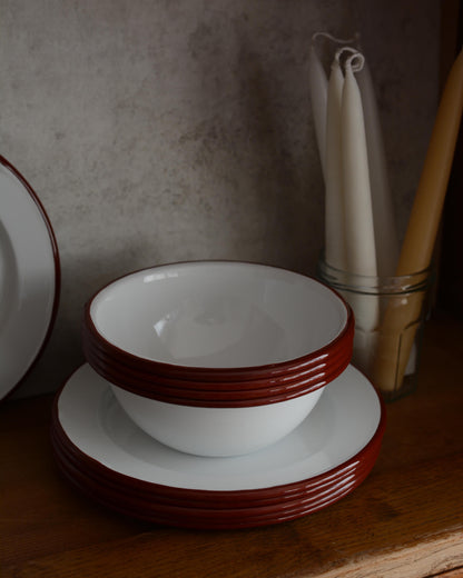 A collection of white and burgundy red enamel bowls and plates.