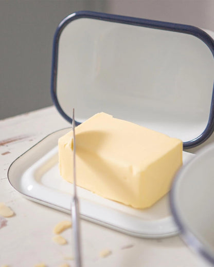 A close up of butter inside a white enamel butter dish.