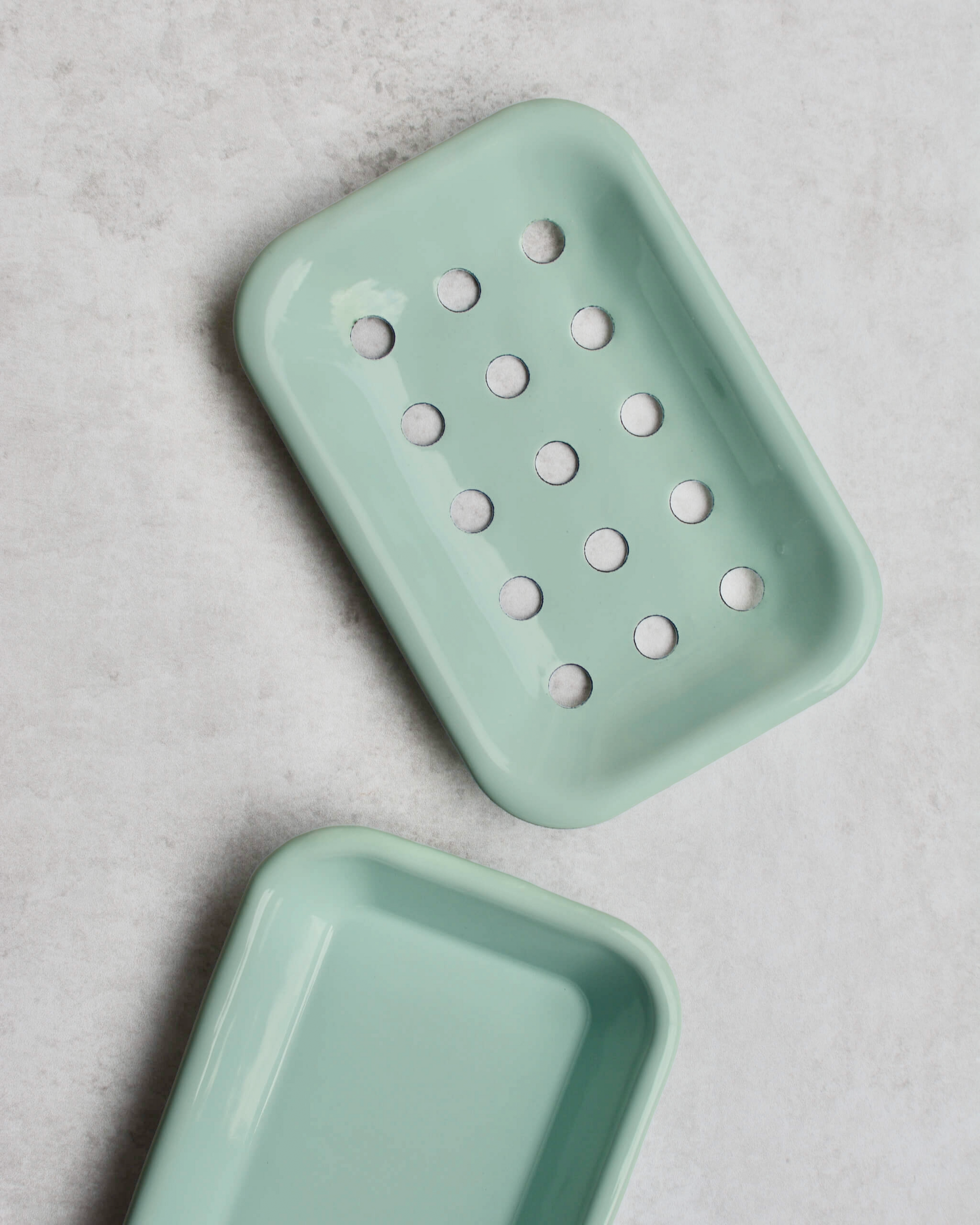 Mint green soap dish with holes on a grey background