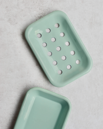 Mint green soap dish with holes on a grey background