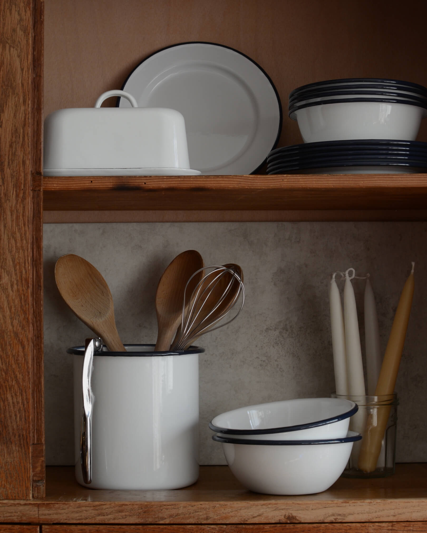 A collection of white and navy enamelware, with bowls, plates utensil holder and butter dish.