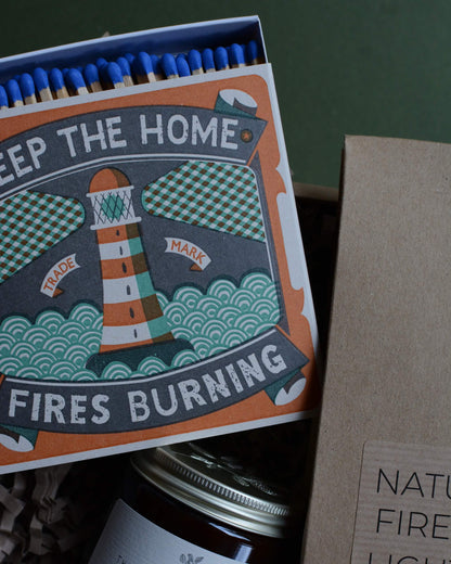 Gift box, containing an amber jar candle, box of matches with a lighthouse design and a pack of natural firelighters.