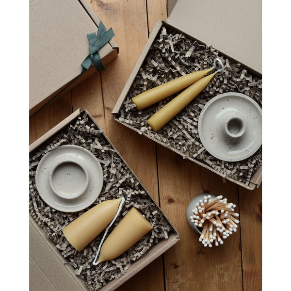 Gift boxes containing beeswax candles and ceramic candle holders. 