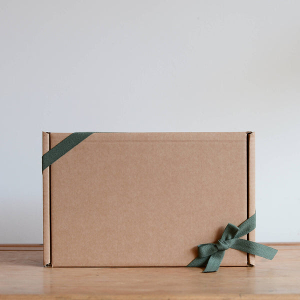 A kraft gift box with green ribbon, tied in a bow.
