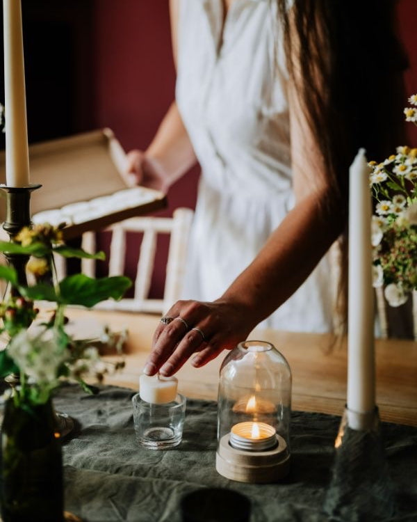 Person arranging candles on a table with a blurred background.