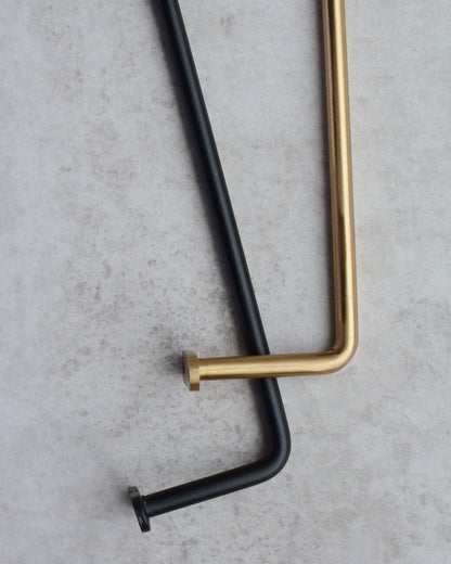 A close-up of a black iron and brass wall-mounted hanging rails.