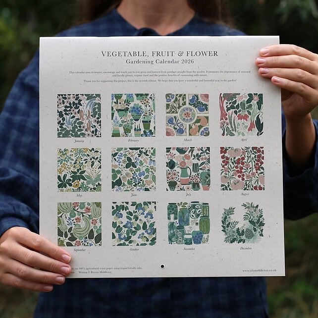 Close up of a person holding a botanical 2026 calendar. Back of the calendar reads "Vegetable, fruit & flower gardening calendar 2026".